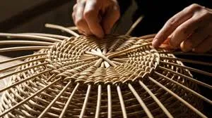 Pengrajin menganyam rotan tradisional di sanggar kerja yang terang.